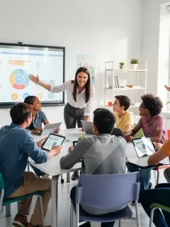 Estudiantes colaborando activamente en un aula moderna con tabletas digitales y pizarras interactivas, fomentando el aprendizaje innovador.